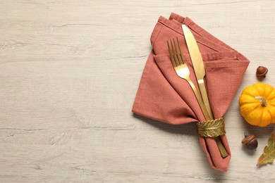 Cutlery, napkin and pumpkin on wooden background, flat lay with space for text. Table setting