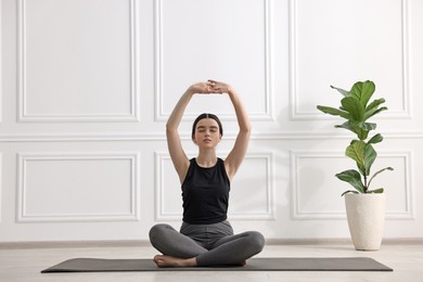 Beautiful girl meditating on mat in yoga studio