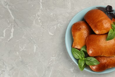Photo of Delicious baked pirozhki and basil on light grey marble table, top view. Space for text