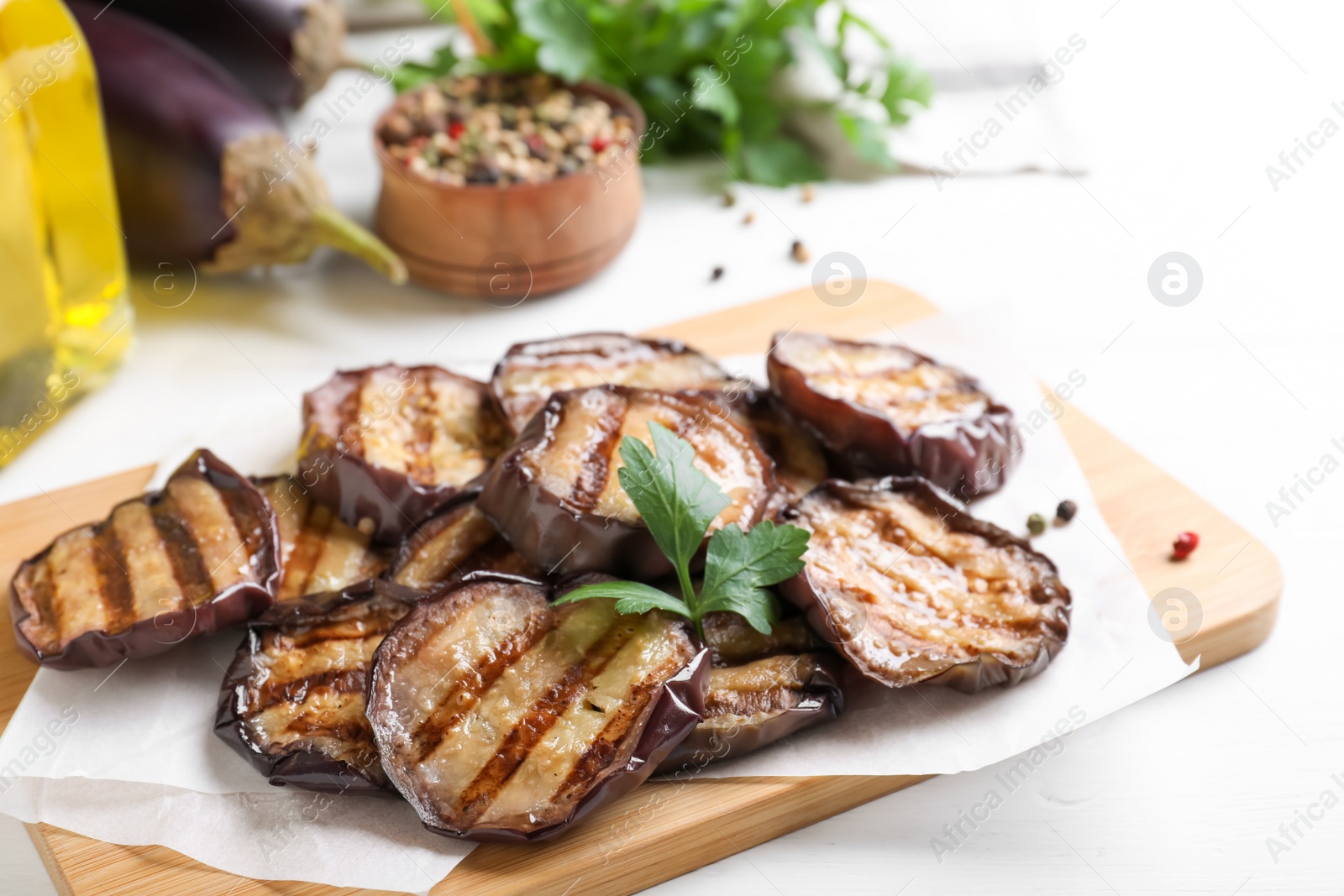 Photo of Delicious grilled eggplant slices with parsley and spices on white wooden table, closeup