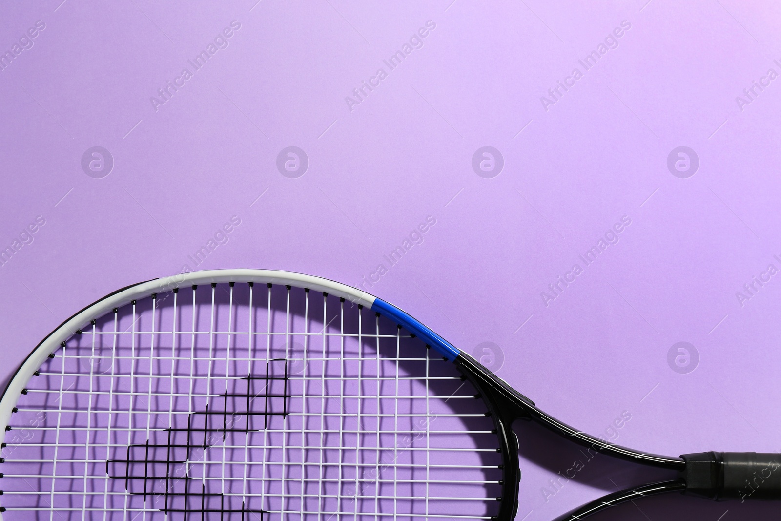 Photo of Tennis racket on violet background, top view. Space for text