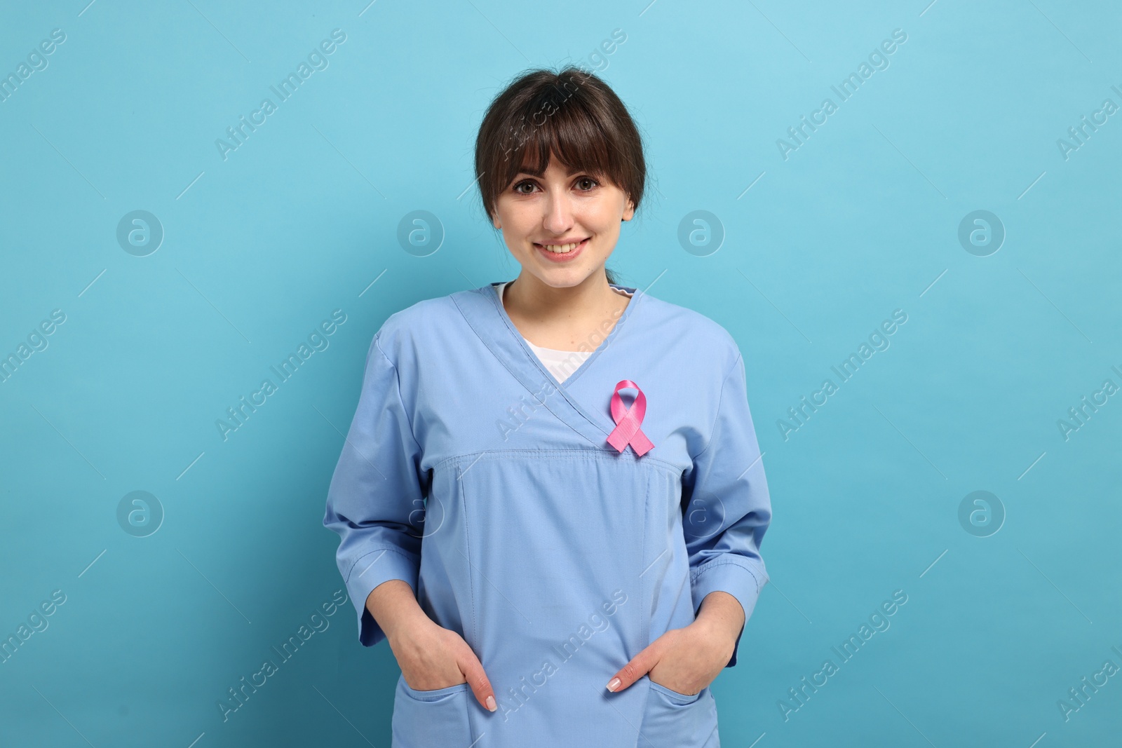 Photo of Mammologist with pink ribbon on light blue background. Breast cancer awareness