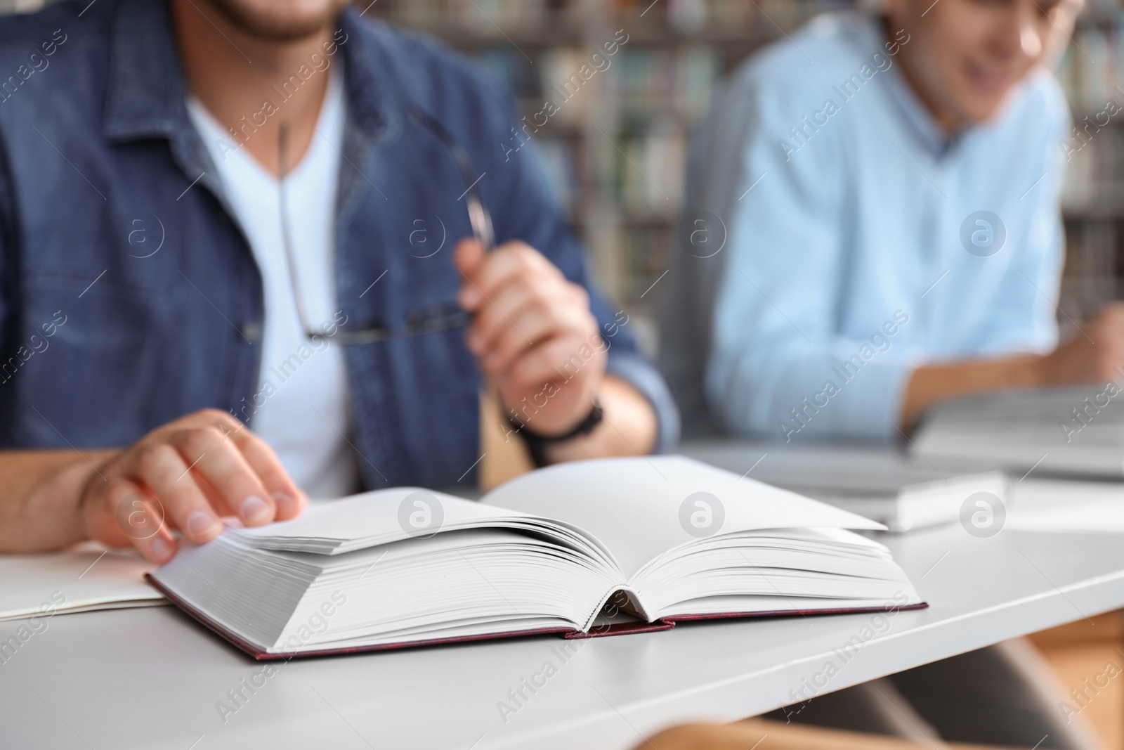 Photo of Young people studying at table in library, closeup