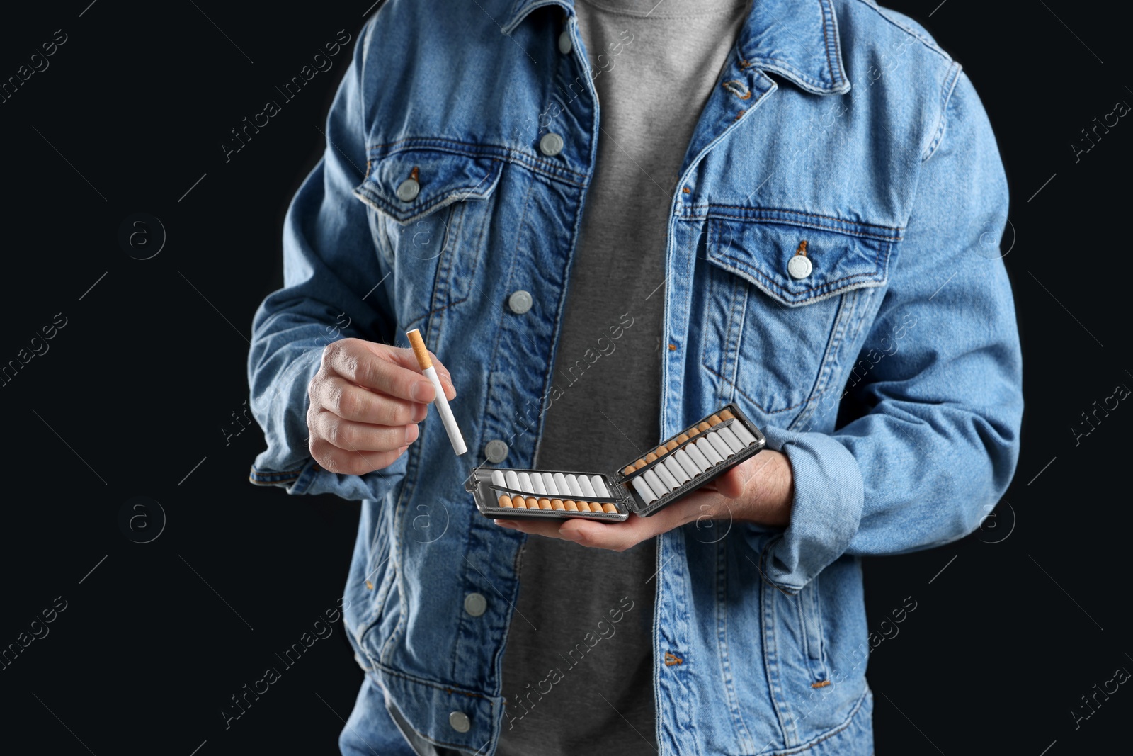 Photo of Man taking cigarette from case on black background, closeup