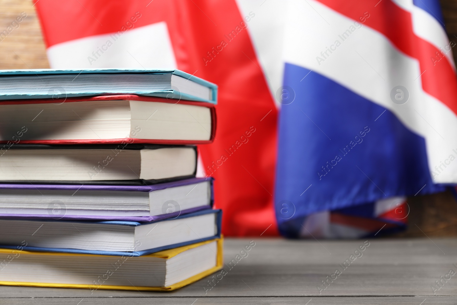 Photo of Learning foreign language. Different books on wooden table near flag of United Kingdom, space for text