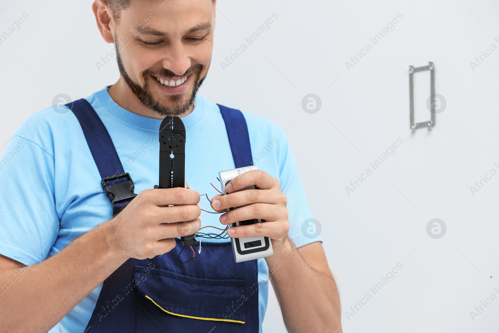 Photo of Young male technician fixing alarm system indoors