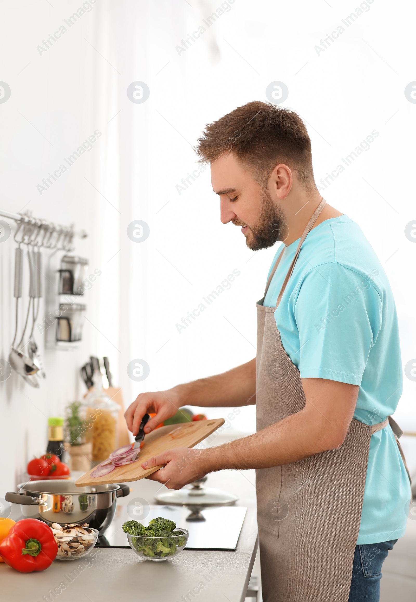 Photo of Young man cooking delicious vegetable soup in kitchen