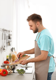 Photo of Young man cooking delicious vegetable soup in kitchen