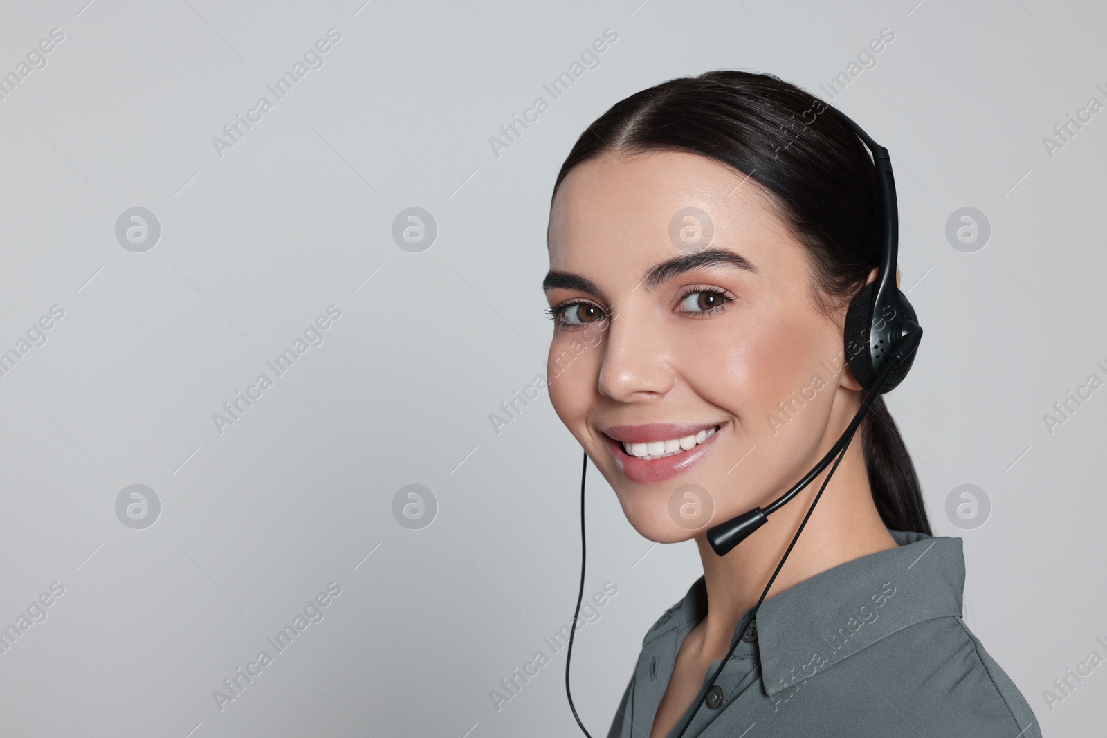 Photo of Hotline operator with modern headset on light grey background, space for text. Customer support