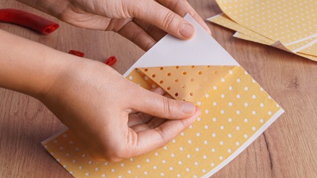 Woman opening pepper plaster at wooden table, closeup