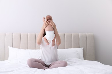 Photo of Mom holding her baby in diaper on bed at home