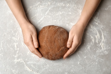 Photo of Woman kneading fresh dough on table, top view
