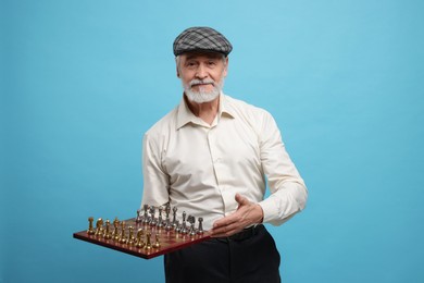 Man with chessboard and game pieces on light blue background