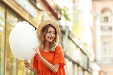 Happy young woman with cotton candy outdoors