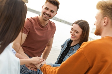 Group of happy people holding hands together, outdoors