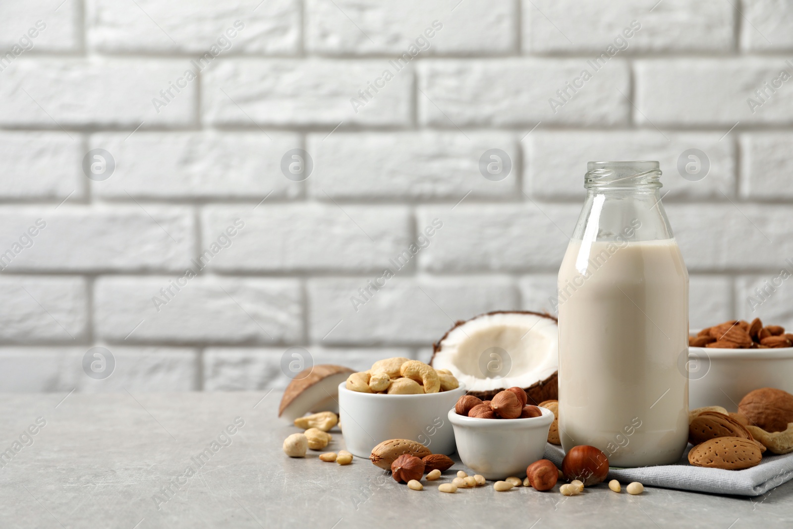 Photo of Vegan milk and different nuts on light table. Space for text