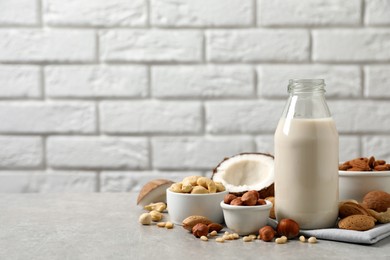 Photo of Vegan milk and different nuts on light table. Space for text