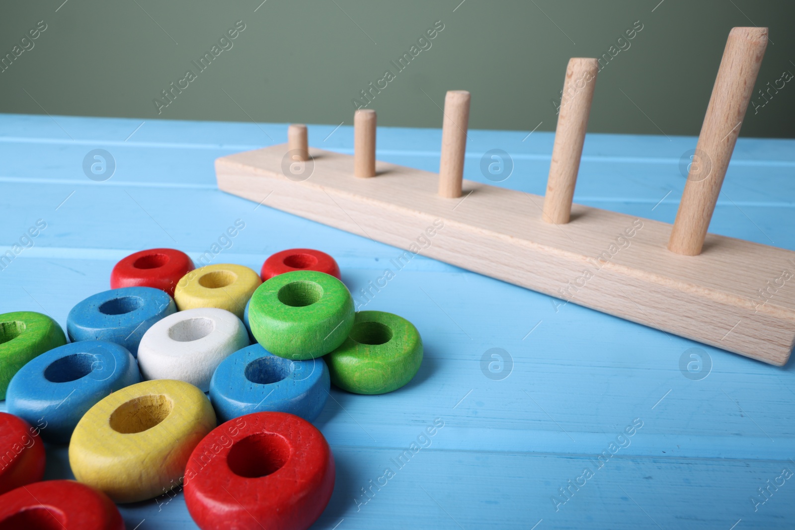 Photo of Stacking and counting game pieces on light blue wooden table, closeup. Motor skills development