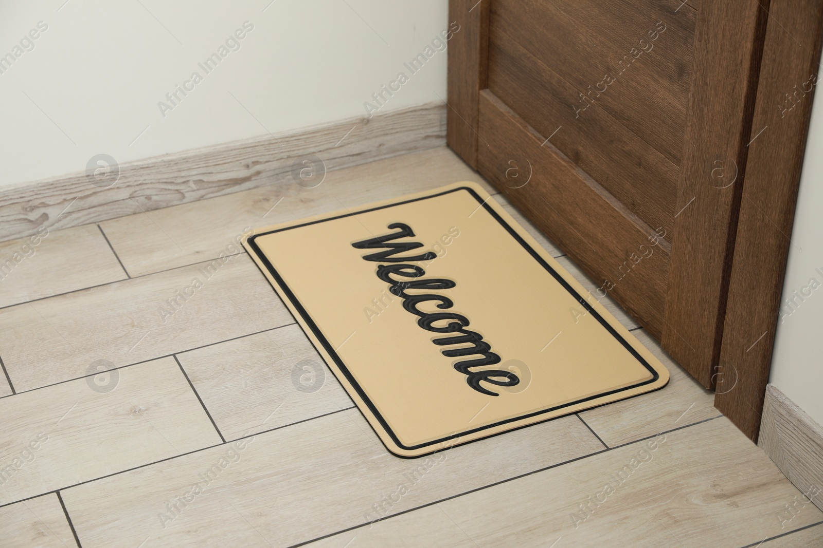 Photo of Beautiful beige doormat with word Welcome on floor near entrance