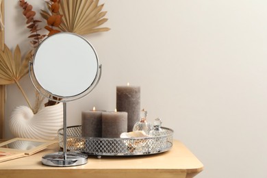 Makeup table with mirror, perfumes and burning candles in room. Space for text
