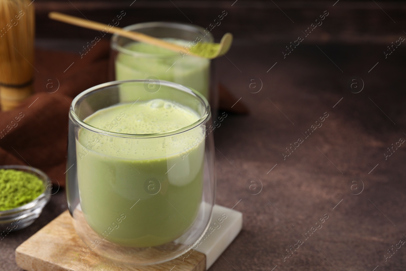 Photo of Glass of tasty matcha smoothie on brown table, closeup. Space for text