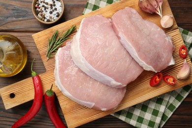 Photo of Pieces of raw pork meat and spices on wooden table, top view