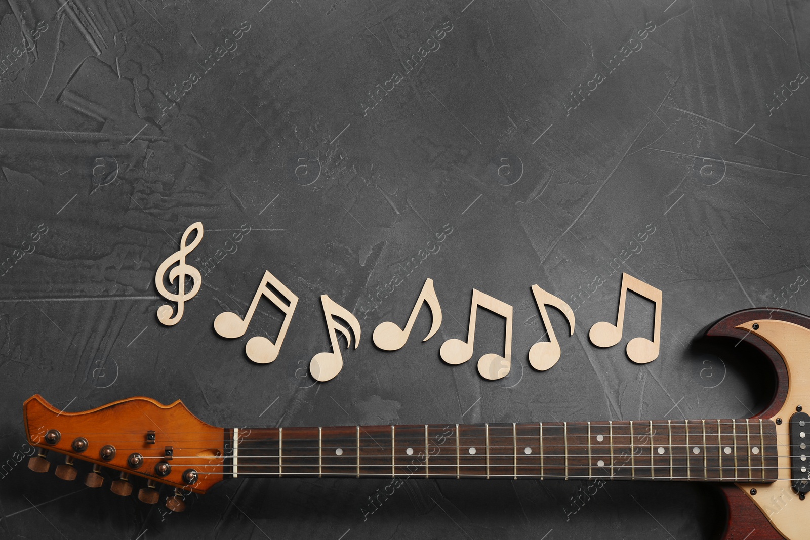 Photo of Music notes and guitar neck on grey background, top view. Space for text