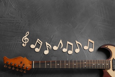 Music notes and guitar neck on grey background, top view. Space for text