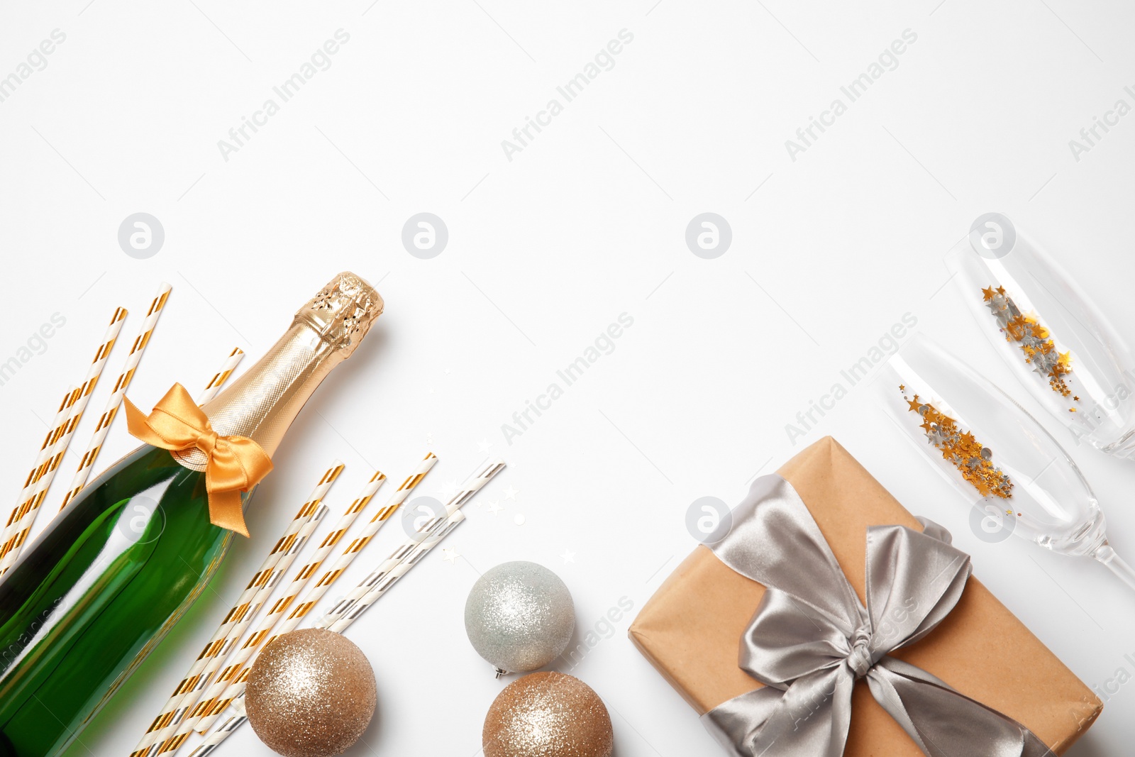 Photo of Creative flat lay composition with bottle of champagne and party accessories on white background. Space for text