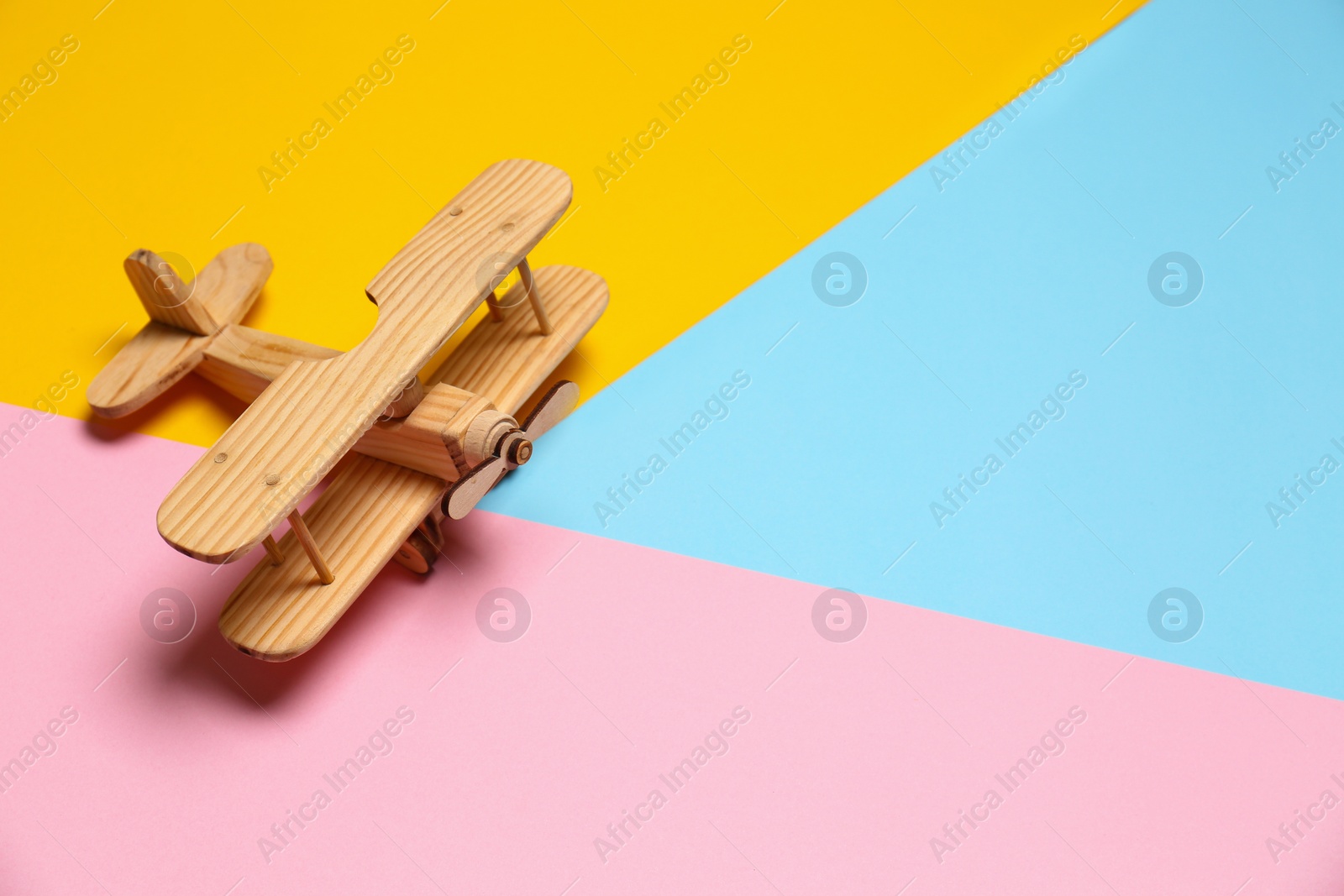 Photo of Wooden decorative airplane on color background, space for text