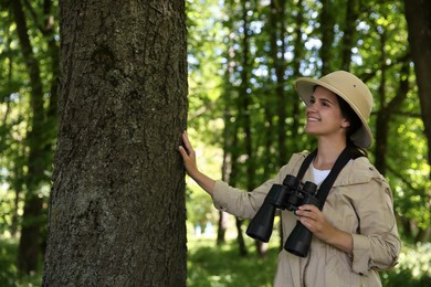 Photo of Forester with binoculars examining tree in forest