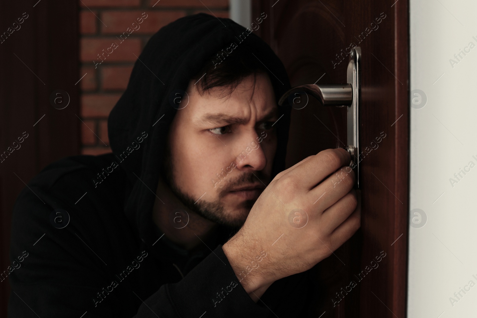 Photo of Man picking door lock to break into house. Criminal offence