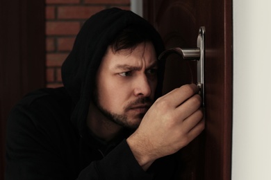 Photo of Man picking door lock to break into house. Criminal offence