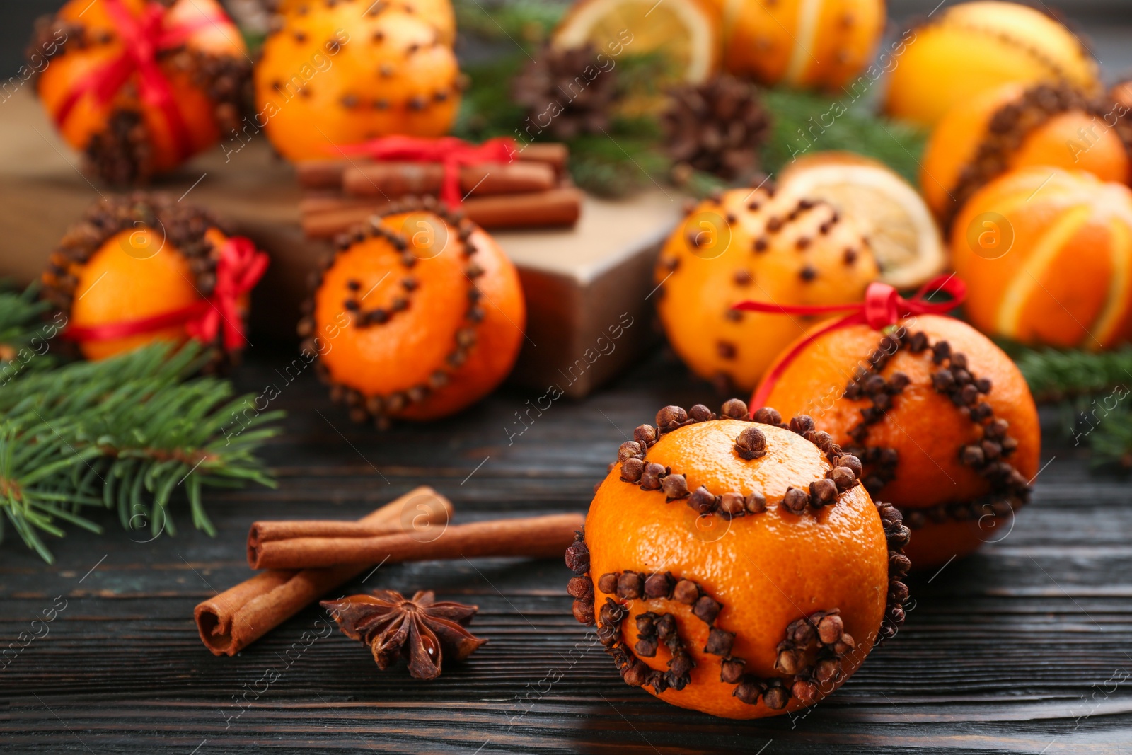 Photo of Pomander balls made of fresh tangerines and cloves on wooden table, space for text