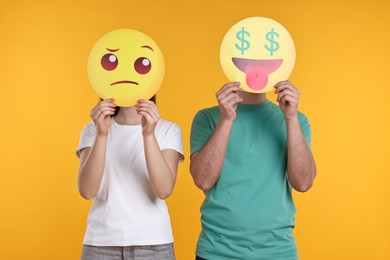 People covering faces with emoticons on yellow background
