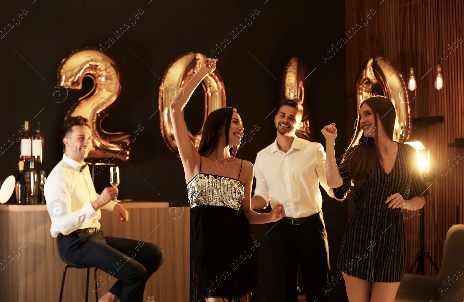 Photo of Young people celebrating New Year in club. Golden 2020 balloons on background