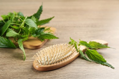 Photo of Stinging nettle and brush on wooden background. Natural hair care