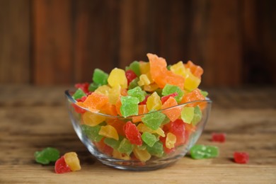 Mix of delicious candied fruits in bowl on wooden table