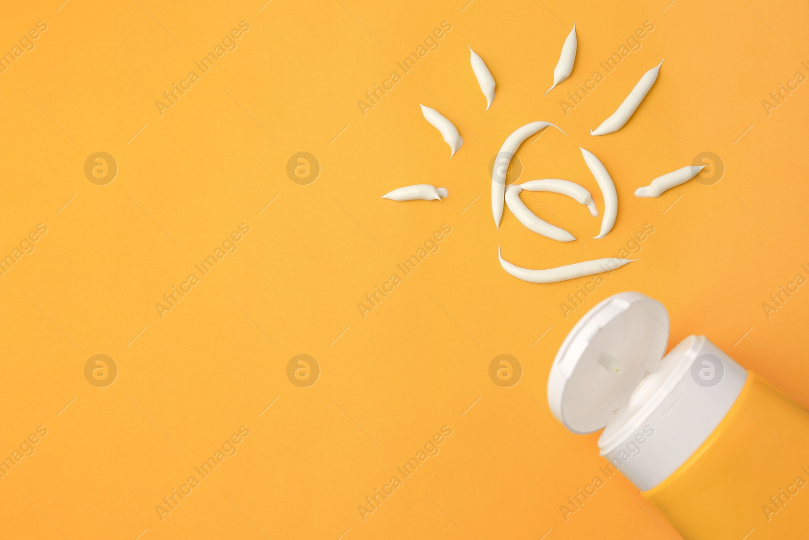 Photo of Drawing of sun and tube with sunscreen on orange background, top view and space for text. Skin protection