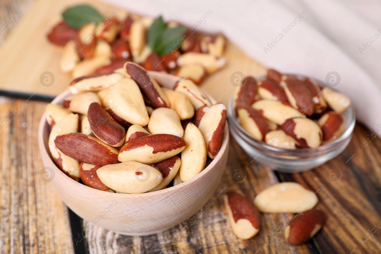 Photo of Bowls with delicious Brazil nuts on wooden table