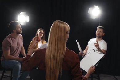 Photo of Professional actors discussing their scripts during rehearsal in theatre