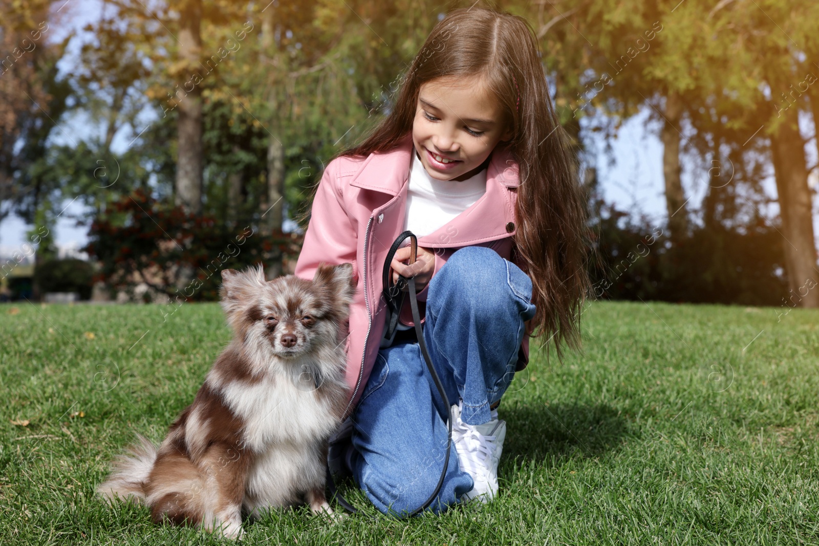 Photo of Little girl with her cute dog in park. Autumn walk