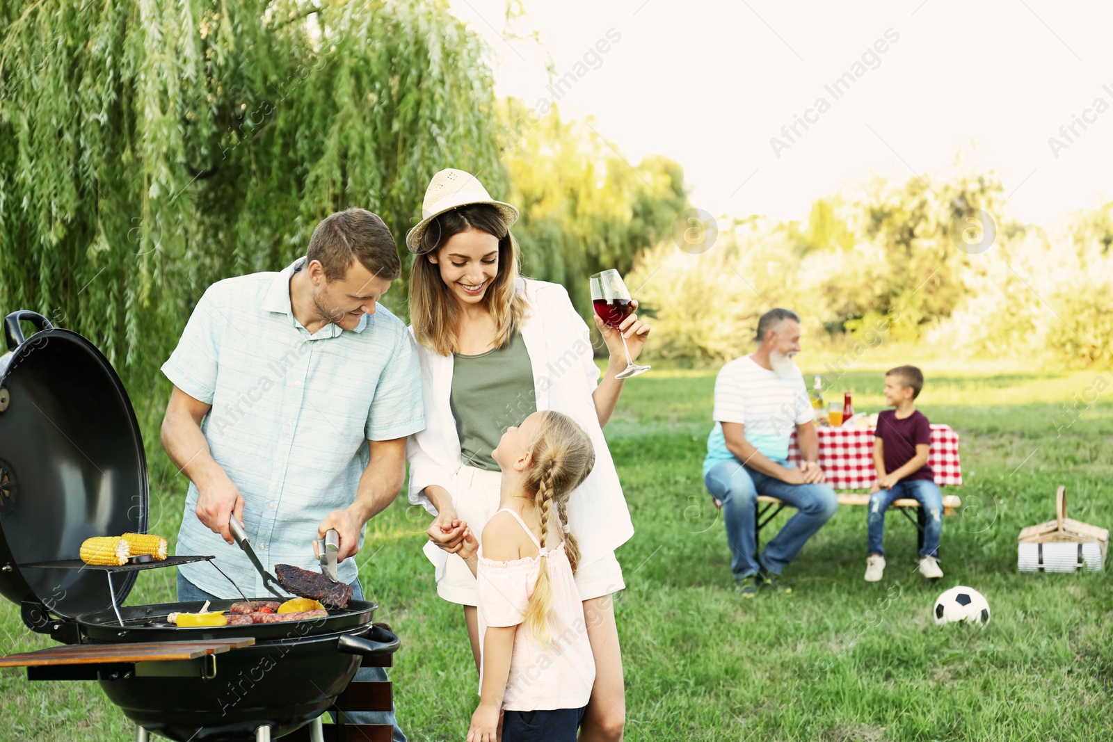 Photo of Happy family having barbecue in park on sunny day