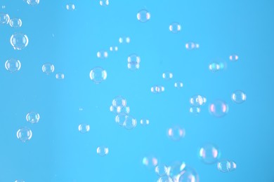 Beautiful transparent soap bubbles on light blue background