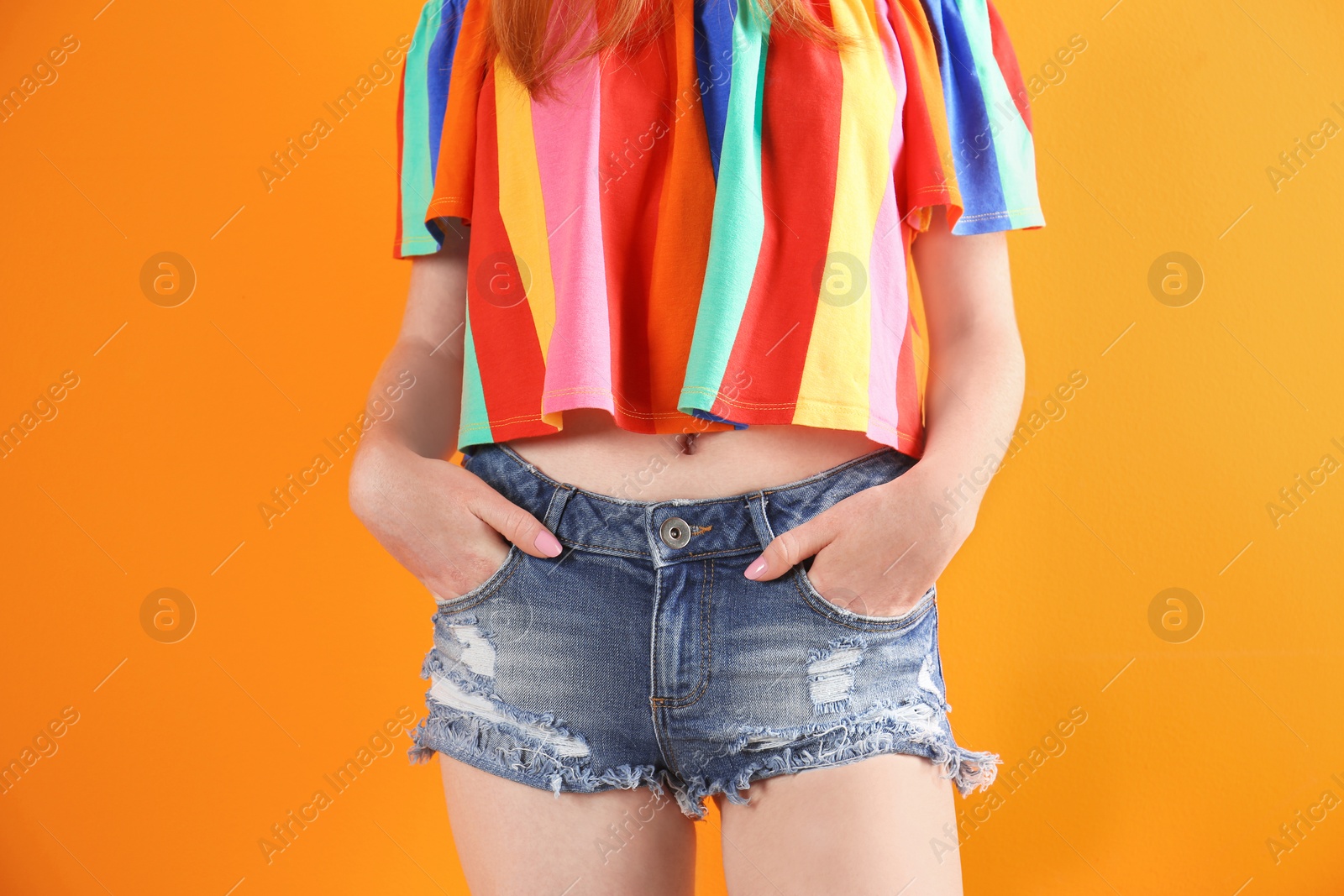 Photo of Young woman in stylish jean shorts on color background