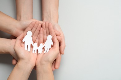 Photo of People holding paper family cutout on light grey background, top view. Space for text