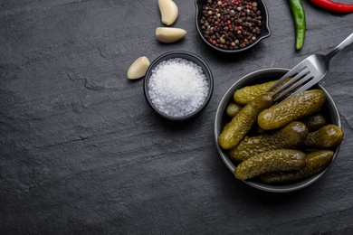 Photo of Bowl of pickled cucumbers and ingredients on black table, flat lay. Space for text