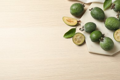 Flat lay composition with fresh green feijoa fruits on wooden table, space for text