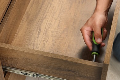 Man with screwdriver assembling drawer, closeup view