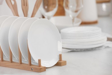 Photo of Drying rack with clean dishes on light table in kitchen